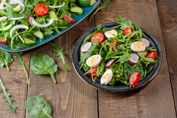 Fresh salad whit arugula, baby spinach, cherry tomato, radish, cucumber, onion and quail egg. Top  view