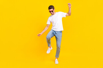 Full body photo of cool young brunet guy dance wear eyewear t-shirt jeans shoes isolated on yellow...