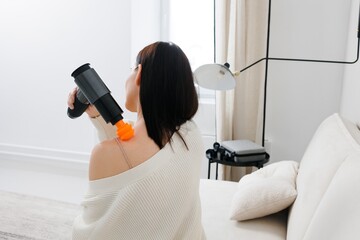 A girl at home massaging with a vibrating massager.  An electric therapeutic pistol massager in her...