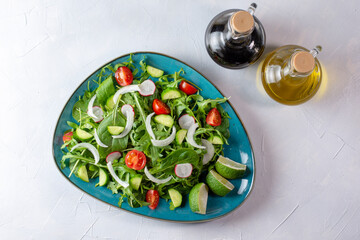 Fresh vegetarian vegetable salad with radish, cucumber, arugula, onion and cherry tomato. Olive oil and balsamic vinegar. Healthy food, top view.