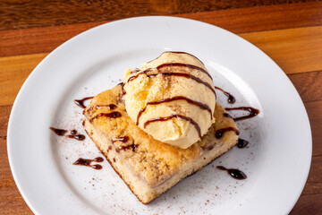 Ice cream with banana cake on a white plate on a wooden table. Delicious dessert.