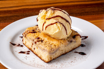 Ice cream with banana cake on a white plate on a wooden table. Delicious dessert.