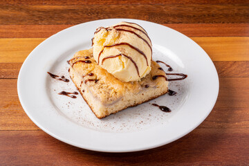 Ice cream with banana cake on a white plate on a wooden table. Delicious dessert.
