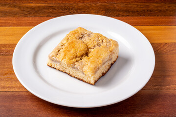 Slice of banana cake on a white plate on a wooden table.
