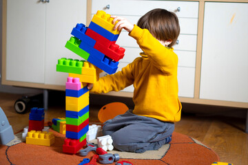 Baby girl builds a tower of  cubes. Child playing with  cubes on the floor