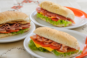 Smoked ham, salami, cheese, lettuce and tomato sandwiches on the table.