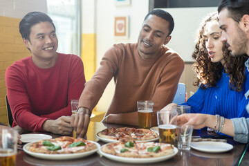 Smiling friends eating pizza at modern pizzeria restaurant - Friendship concept with multi ethnic people enjoying time together having fun at pizzeria with pizza and beer pints - obrazy, fototapety, plakaty