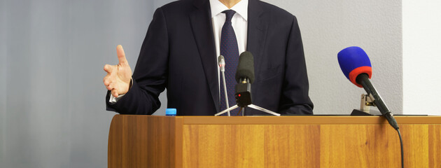 Man - politician, businessman, official or lawyer speaks from the podium in front of microphones....