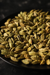 Cardamom seeds in a black bowl