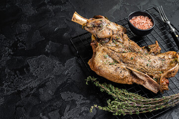 Barbecue Roasted lamb mutton shoulder meat with herbs and spices. Black background. Top view. Copy...