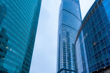 Fototapeta na wymiar The tops of modern corporate buildings in snowfall. Low angle view of skyscrapers.
