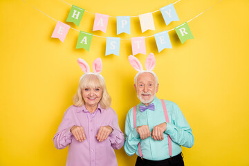 Portrait of two attractive trendy cheery funny grey-haired spouses easter having fun isolated over bright yellow color background