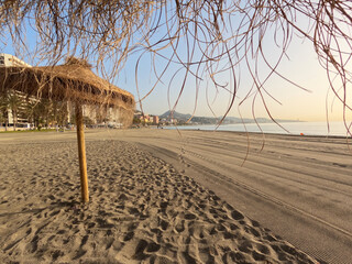 Summer umbrellas on the beach at la Malagueta urban sand beach at sunrise, Costa del Sol, Malaga,...