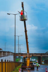 with a crane men working at high voltage line in a highway.