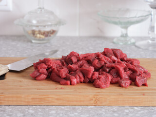 Chopped up beef fillet on a cutting board with a kitchen knife nearby