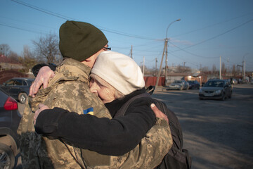 Elderly mother says goodbye to her military son. Mom hugs a Ukrainian soldier. Militarization....