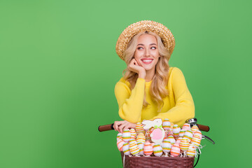 Photo of adorable dreamy lady dressed yellow pullover headwear driving cycle empty space isolated green color background