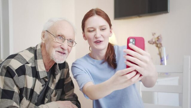  A woman teaches her grandfather how to take a selfie on the phone. He likes it