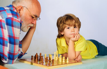 Grandfather and grandson playing chess. Grandpa teaching his grandchild to play chess. Checkmate.