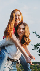 Two Happy cheerful young loving girl friends having fun on nature background. Two friends Gen z Millennials dancing and playing in meadow