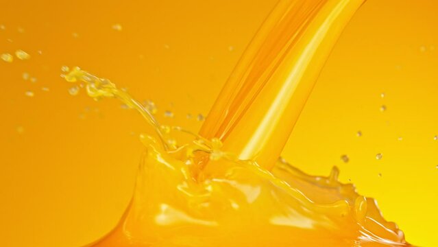 Pouring orange juice with splashes. Macro background. Filmed on a high-speed cinema camera at 1000 fps.