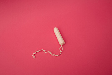 Medical female tampon on a pink background. Hygienic white tampon for women. Cotton swab. Menstruation, means of protection.
