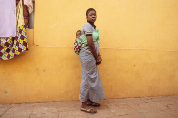 Portrait of mother and son.African Woman carrying her baby boy on her back in a street in...