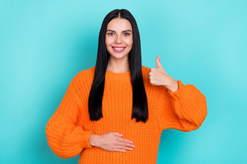 Photo of sweet adorable woman wear orange sweater arm stomach thumb up isolated turquoise color...
