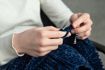 Young woman knitting warm colorful sweater at home. Concept of needlework. Close up