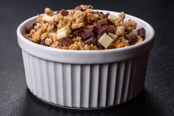Tasty healthy breakfast with cereals, granola, chocolate, milk and jam on a dark concrete background