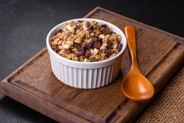 Tasty healthy breakfast with cereals, granola, chocolate, milk and jam on a dark concrete background