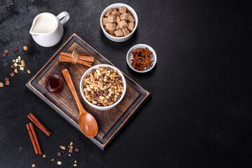 Tasty healthy breakfast with cereals, granola, chocolate, milk and jam on a dark concrete background