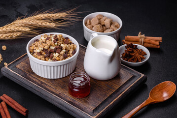 Tasty healthy breakfast with cereals, granola, chocolate, milk and jam on a dark concrete background