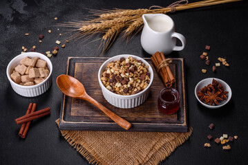 Tasty healthy breakfast with cereals, granola, chocolate, milk and jam on a dark concrete background
