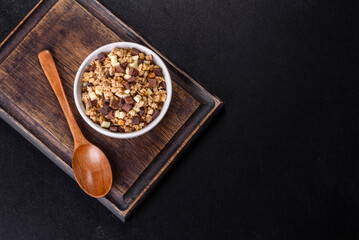 Tasty healthy breakfast with cereals, granola, chocolate, milk and jam on a dark concrete background