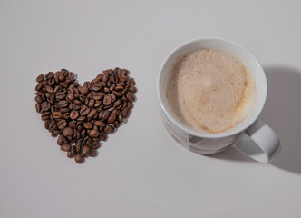 a cup of cappuccino and coffee beans with a heart