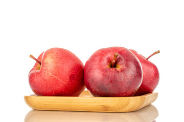 Three ripe red apples on a bamboo plate, macro, isolated on a white background.