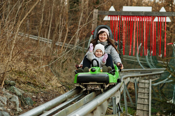 Mother with daughter ride electric sleigh on rails.