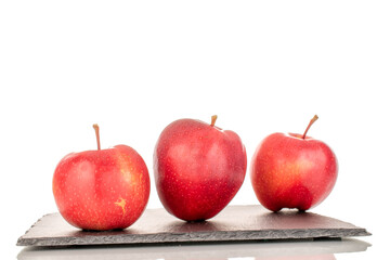 Three ripe red apples on a slate stone, macro, isolated on a white background.