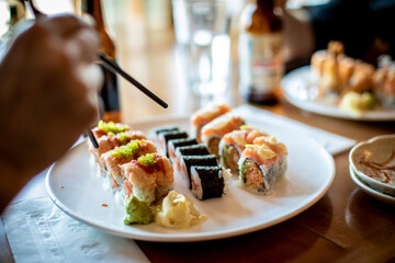 A hand holding chopsticks about to pick up a sushi roll.