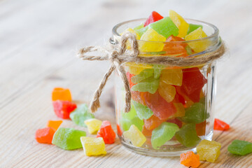 Candied fruits in glass jar on wooden background