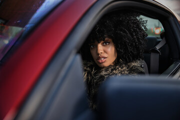 Portrait of a woman in a red sports car looking into camera.