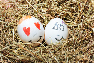 Easter painted eggs in a nest of grass. Cute happy and romantic faces. Loving hearts. Minimal concept. Copy space.
