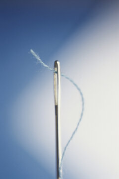 Close-up of thread through the eye of a needle
