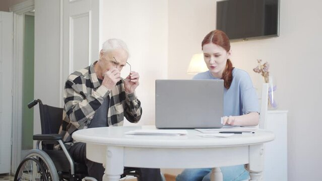 Woman explaining to her grandfather how to use a laptop