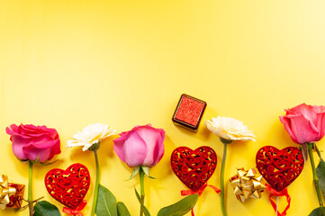 Flowers and decor in the form of patterned hearts on a yellow background. Roses and gerberas on yellow.