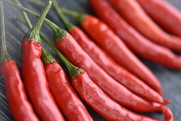 red chili peppers in a group on a dark wooden cutting board