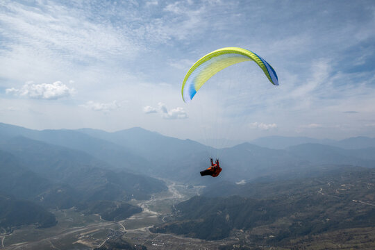 A paraglider carves a turn with views of Nepal, Himalayas in distance.