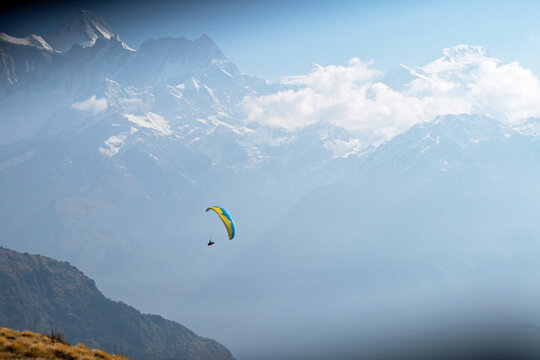 Wide shot of a paraglider in Nepal with mountain range in background. 