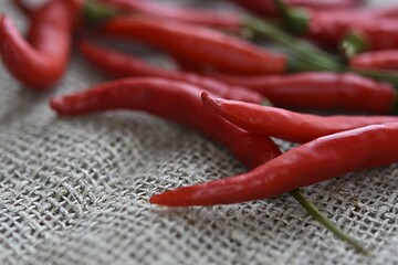 red chili peppers in a group on a dark wooden cutting board